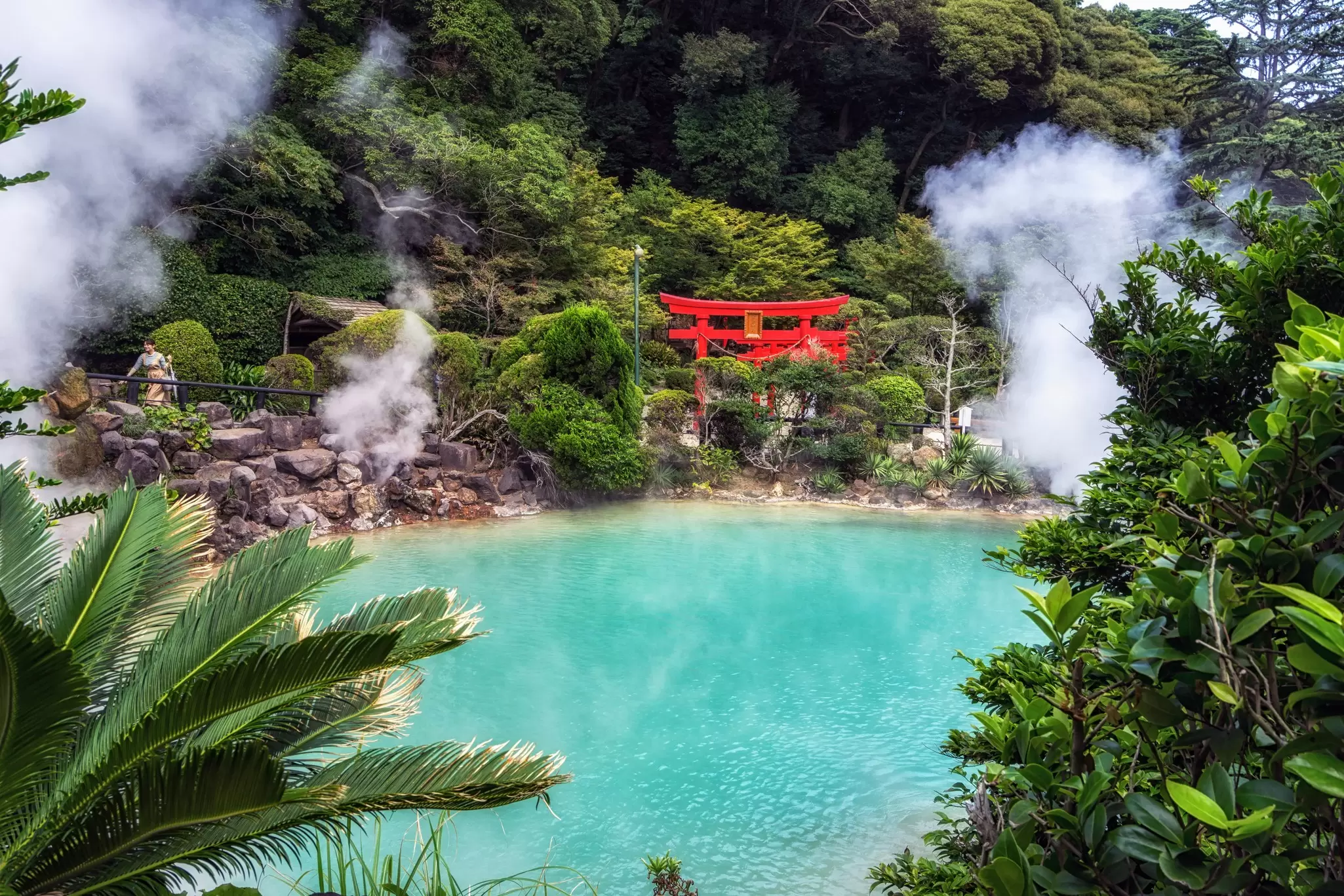 A bright blue pool of water with steam rising in a Japanese tourist attraction, Beppu's "hell"