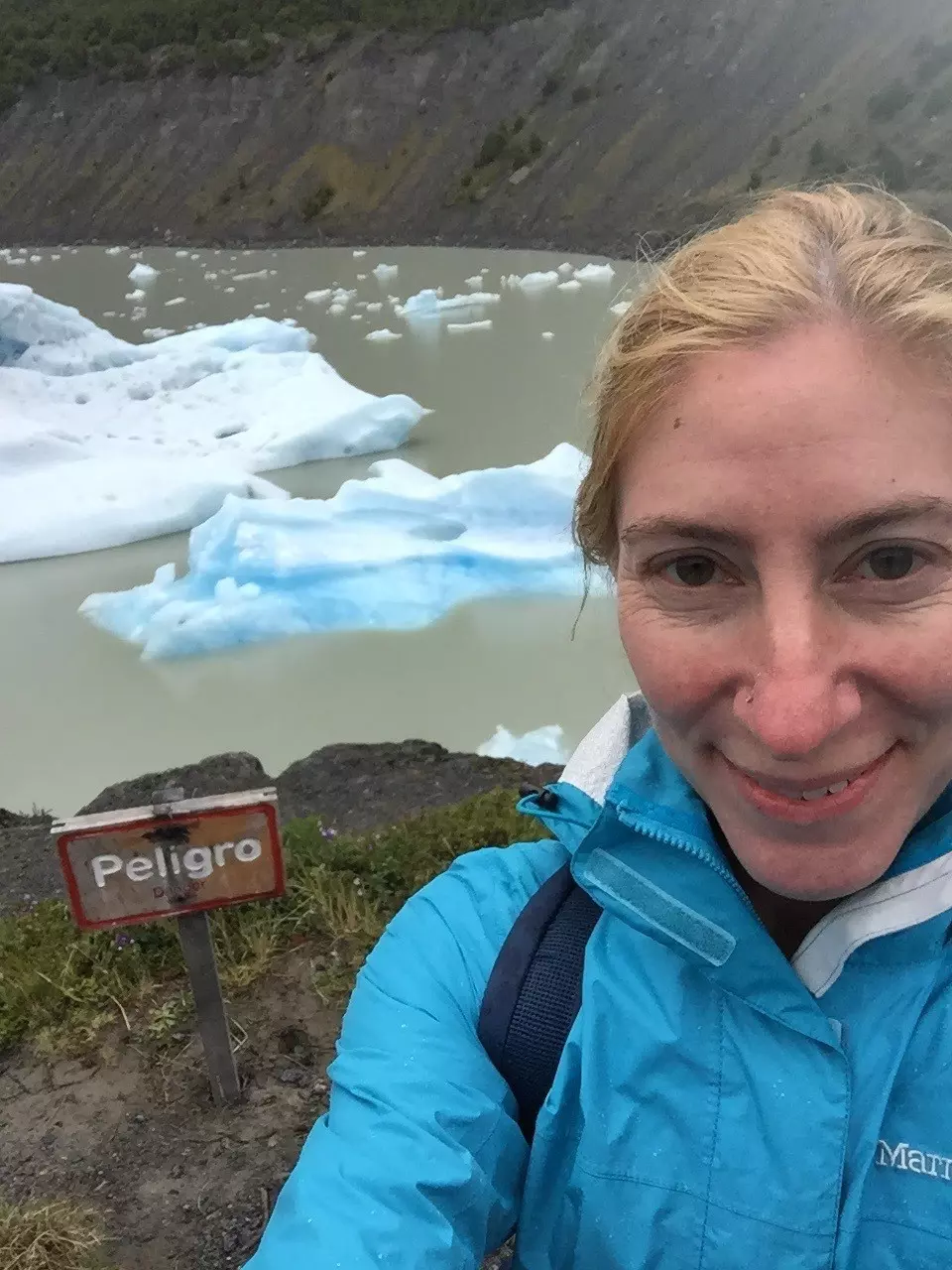 Caroline Trefler in Patagonia with an icy lake and part of a mountain behind her