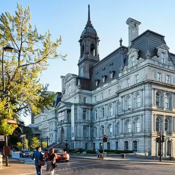 A couple crosses the street in front of the City Hall on a sunny summer afternoon in Montreal, Canada.
