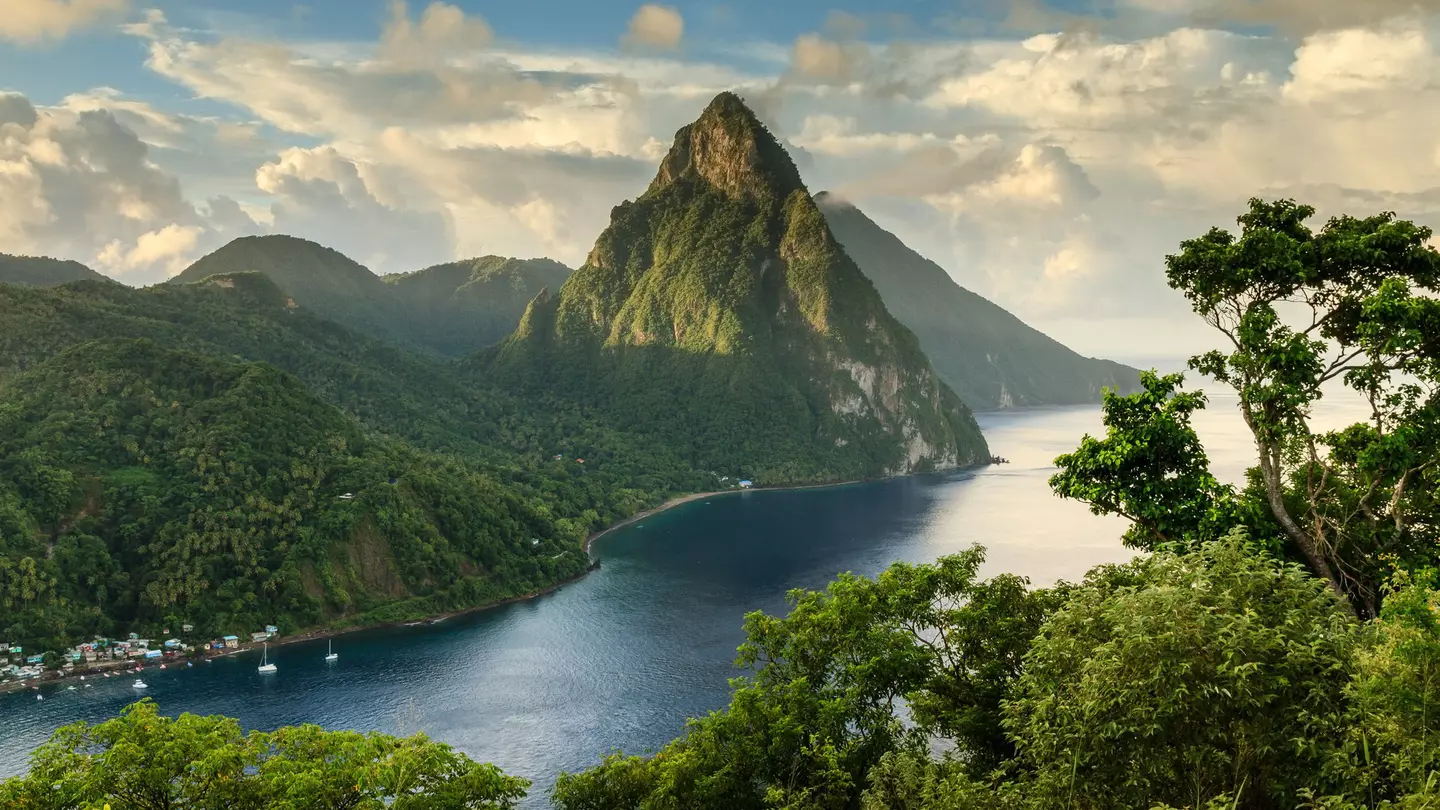 View of St. Lucia's Pitons (Petit Piton & Gros Piton) from an elevated viewpoint with the lush green rainforest and deep blue bay of Soufrière in the foreground.