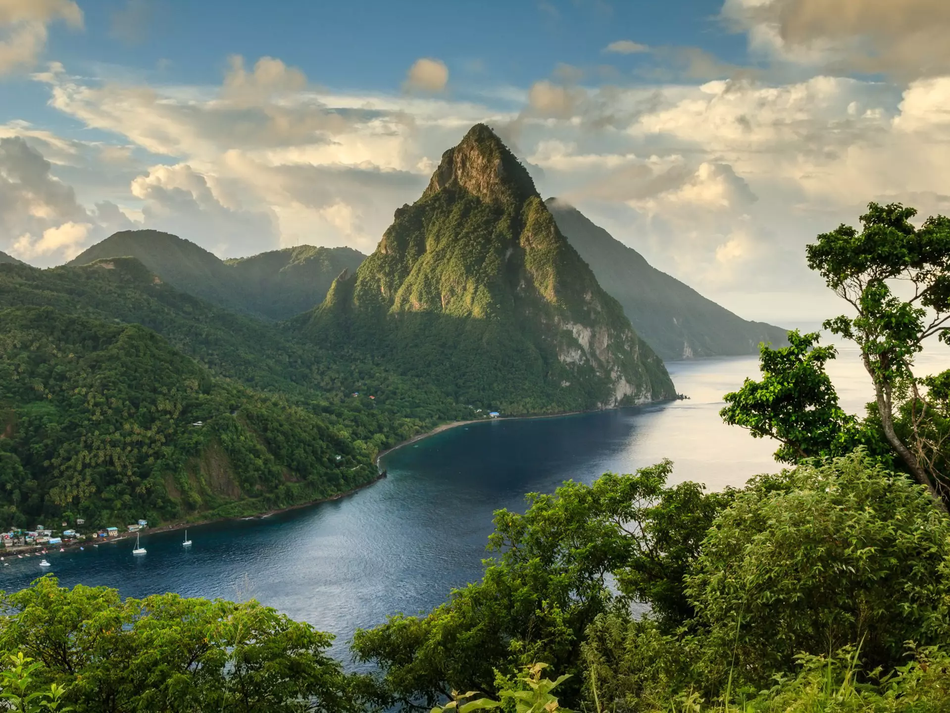 View of St. Lucia's Pitons (Petit Piton & Gros Piton) from an elevated viewpoint with the lush green rainforest and deep blue bay of Soufrière in the foreground.