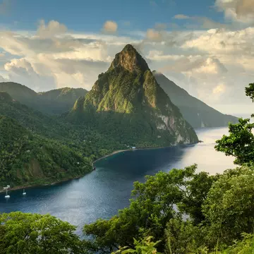 View of St. Lucia's Pitons (Petit Piton & Gros Piton) from an elevated viewpoint with the lush green rainforest and deep blue bay of Soufrière in the foreground.