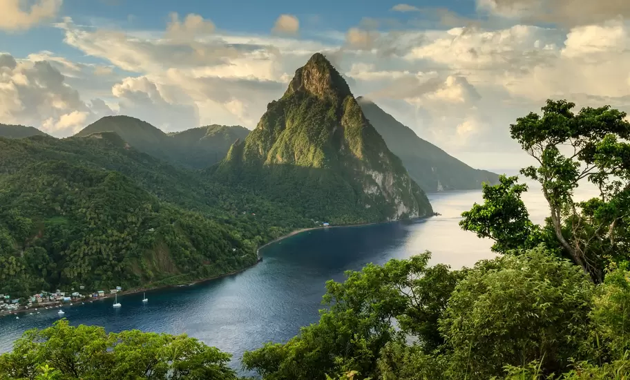 View of St. Lucia's Pitons (Petit Piton & Gros Piton) from an elevated viewpoint with the lush green rainforest and deep blue bay of Soufrière in the foreground.