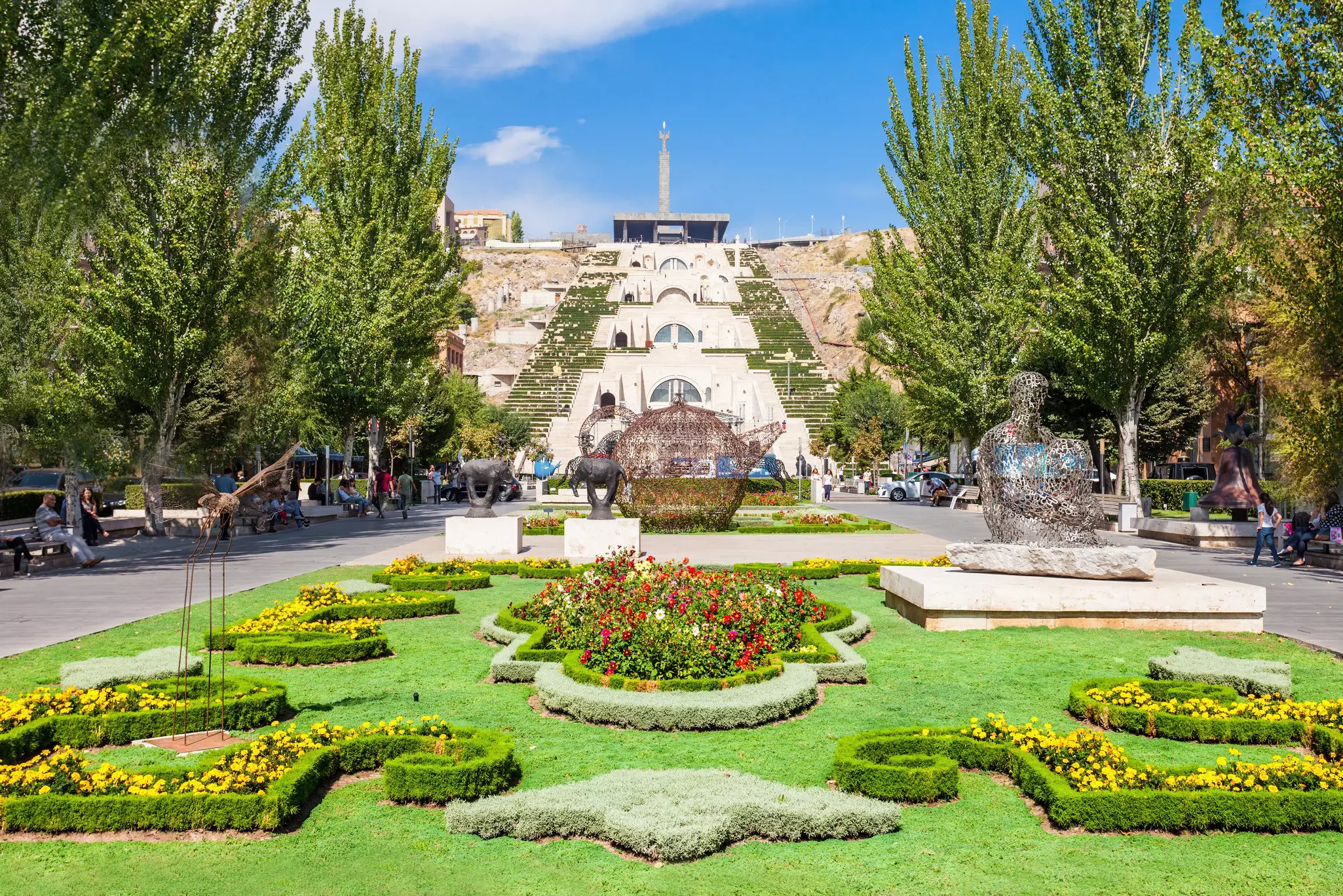 A sprawling garden with decorative bushes and trees in front of The Cascade in Yerevan, Armenia.