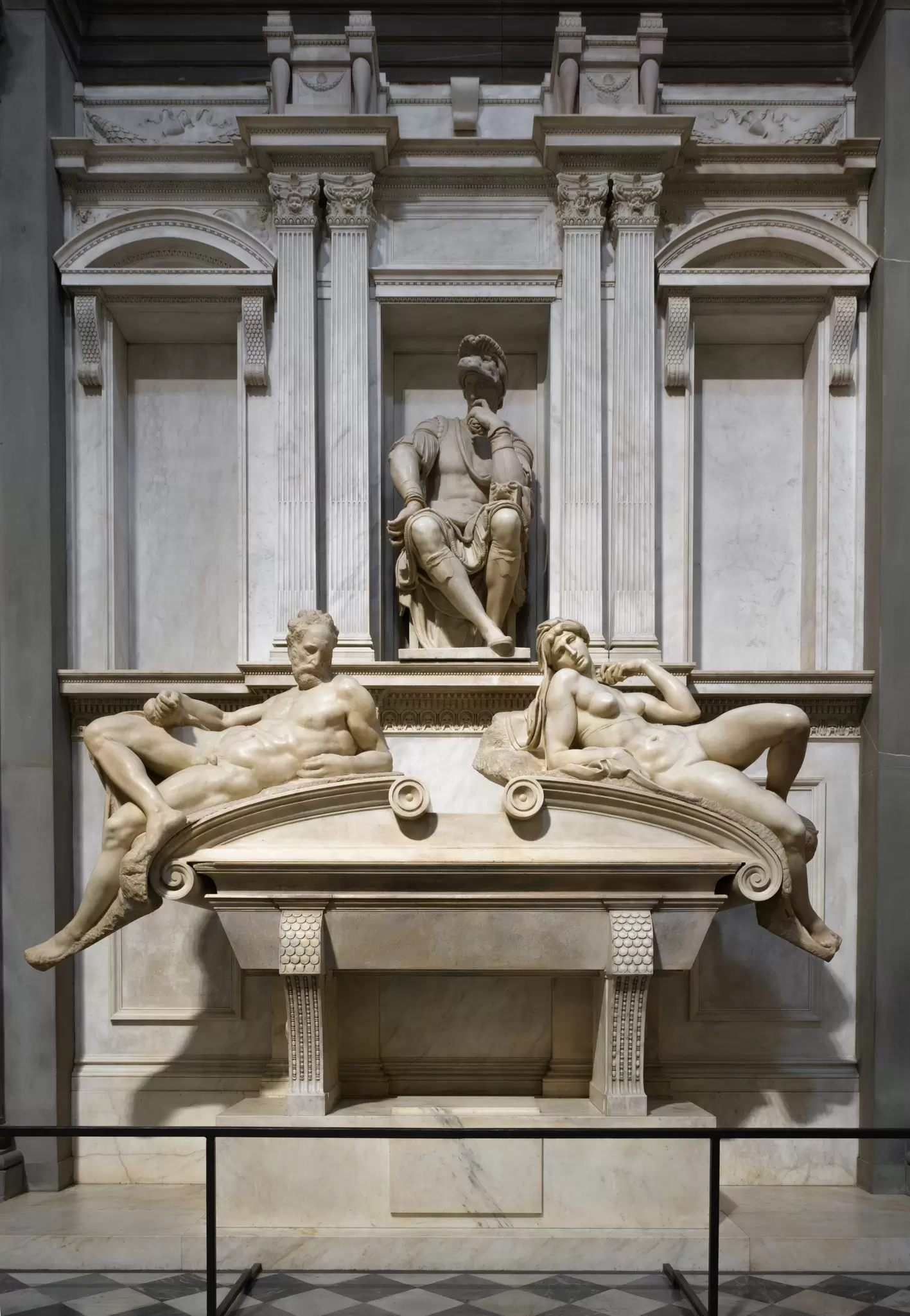 A tomb in a church is topped by realistic marble sculptures of human figures