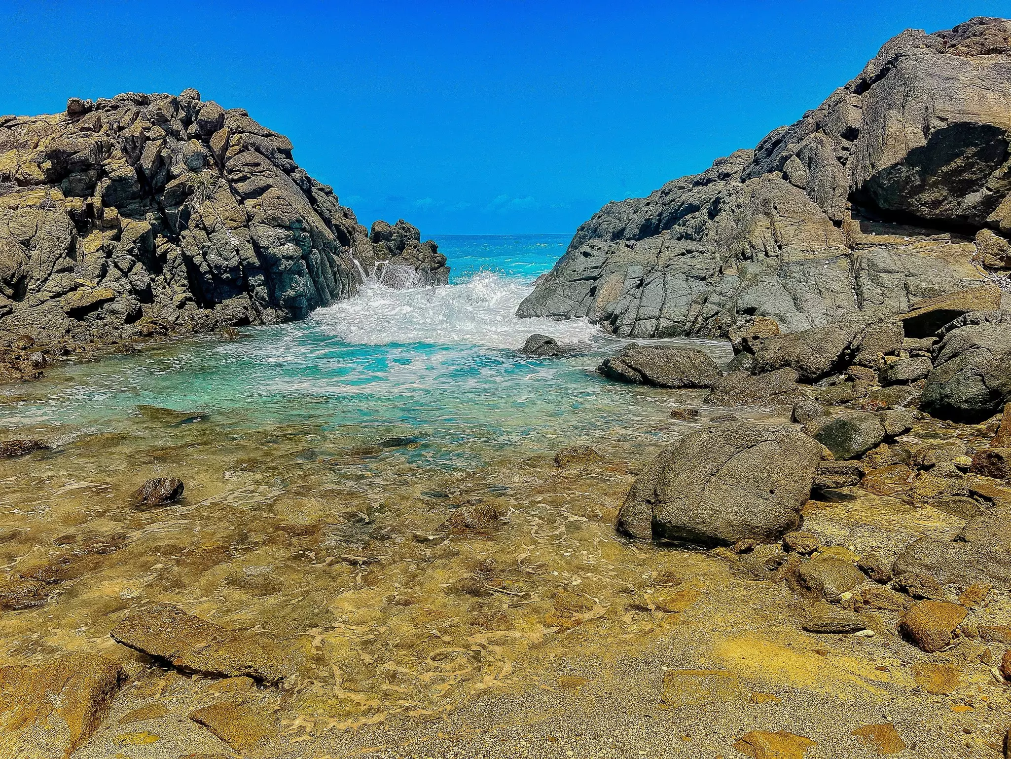 Waves crash in a rocky inlet on a tropical island.