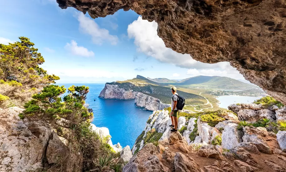 Capo Caccia, hiker admiring the view from a cave. Sardinia island, Italy