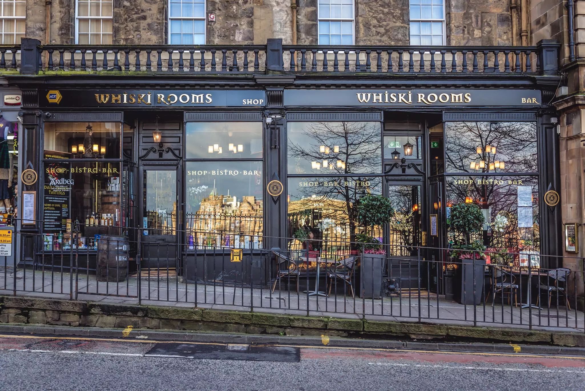 The facade of a bar and shop. "Whiski Rooms" is in gold letters above the door to each entrance