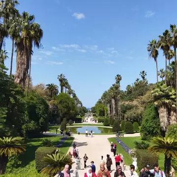 Crowd walking from fountain and palm trees in Botanical garden El-Hamma beautiful and colorful background, Algiers - Algeria.