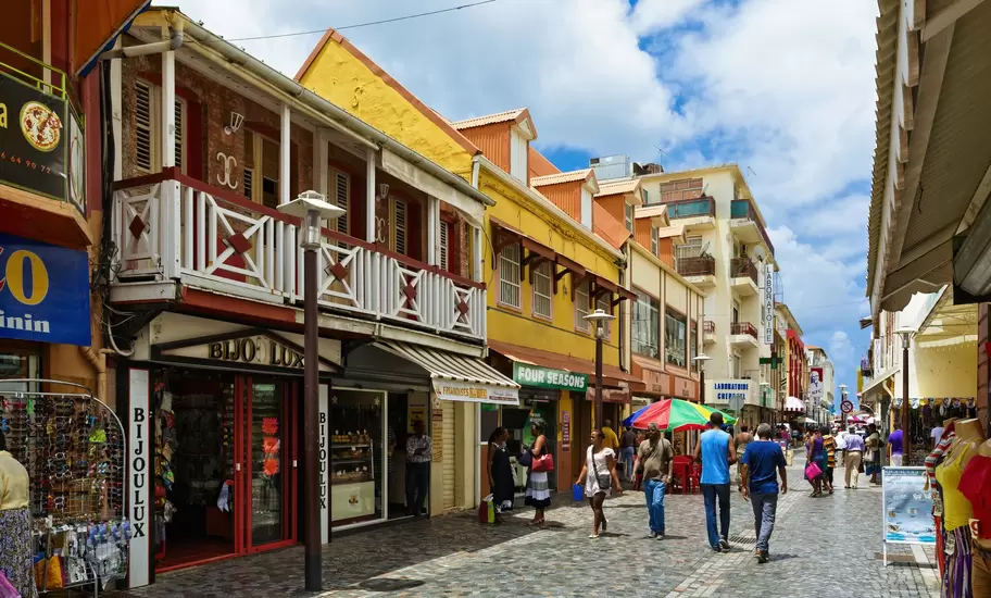 Pedestrian shopping street in Fort-de-France, Martinique, lined with colourful balconied buildings and shops signed Bijoulux