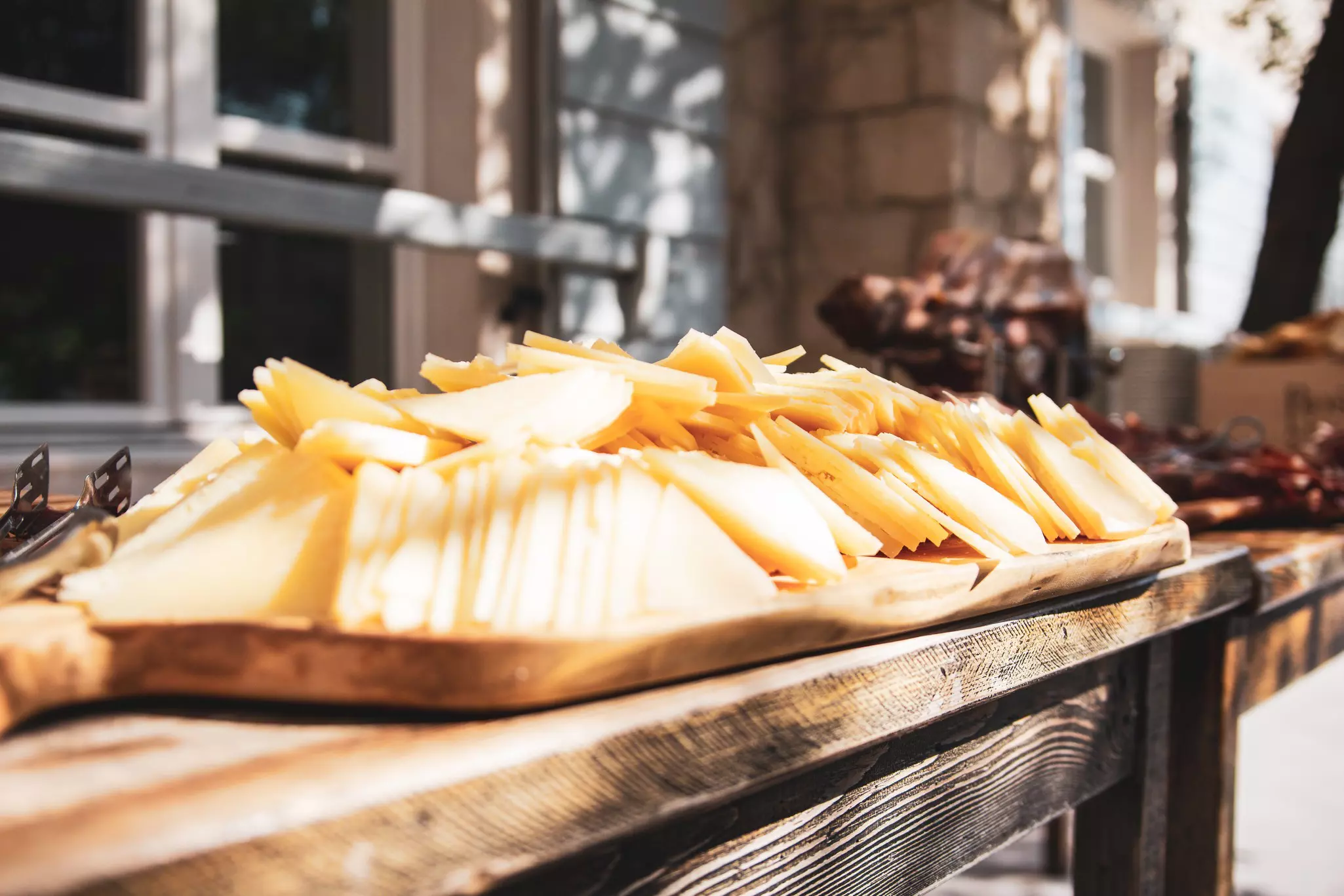 Slices of yellow cheese piled high on a large wooden platter