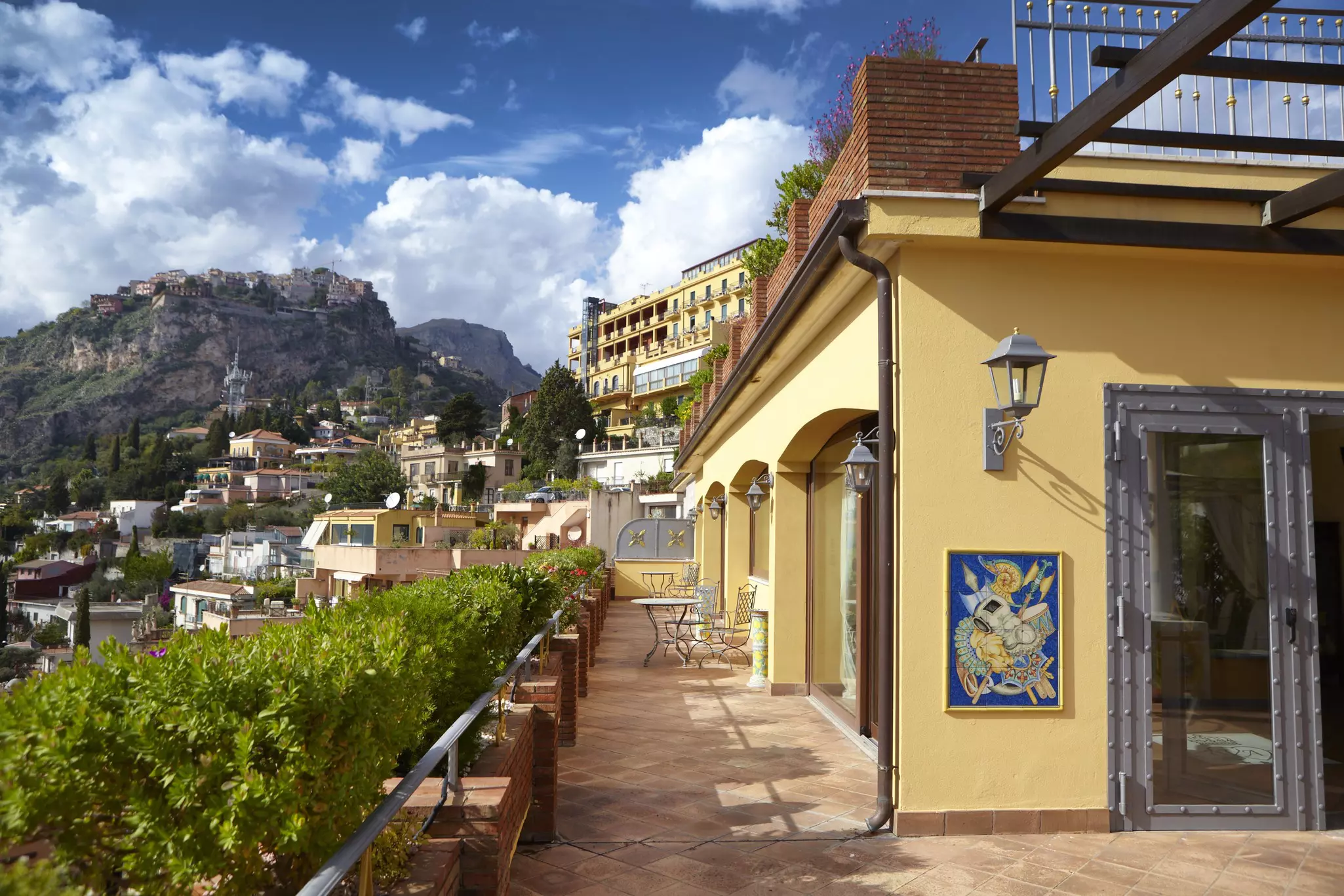 Balcony of a yellow building with views of a town nestled in verdant hills
