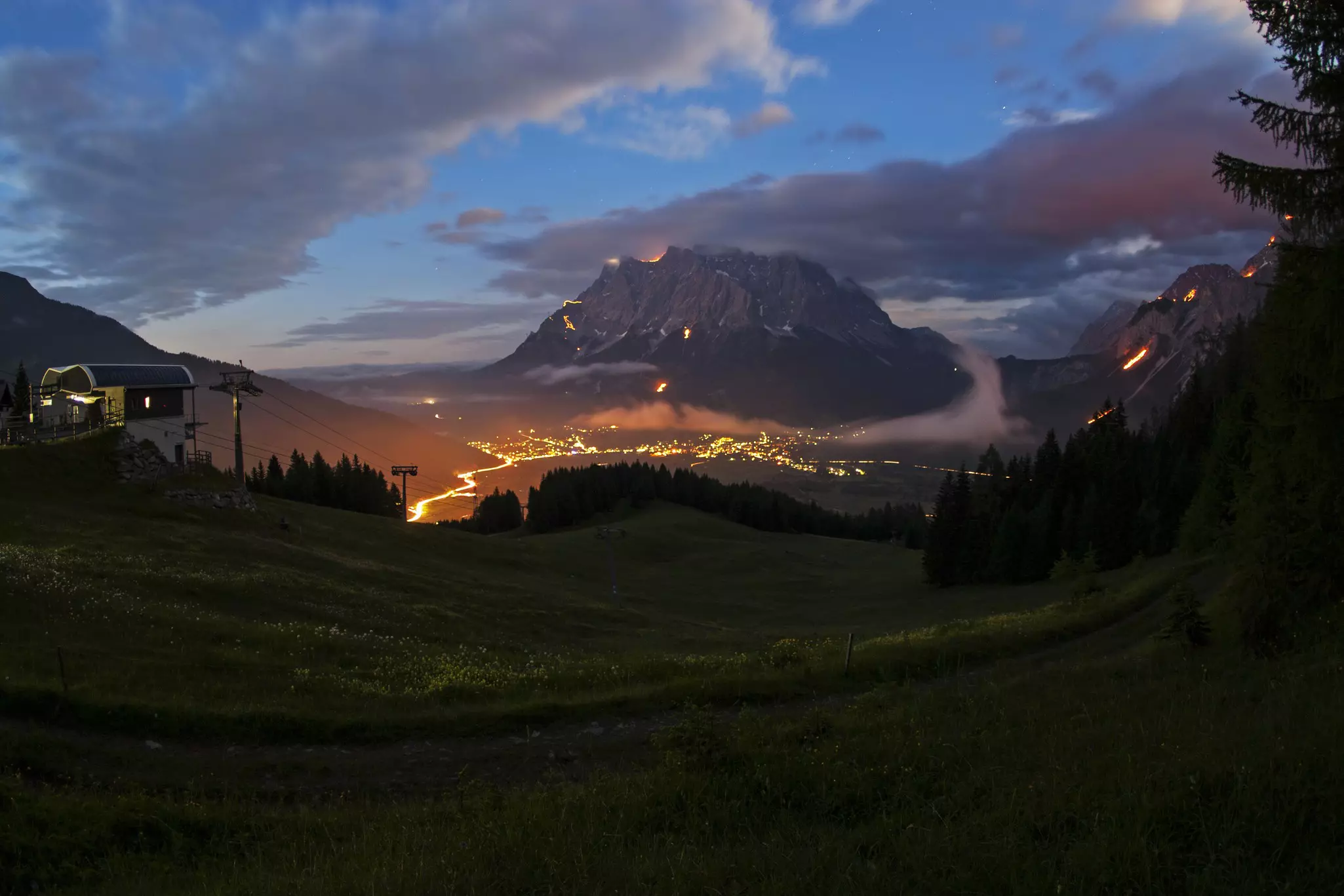 Mountains are glowing red and orange in the darkness, lit by many fires