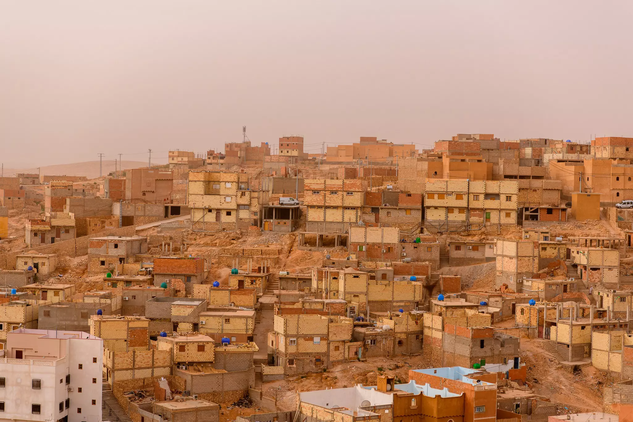 An Algerian city of low golden buildings under a dusky sky.