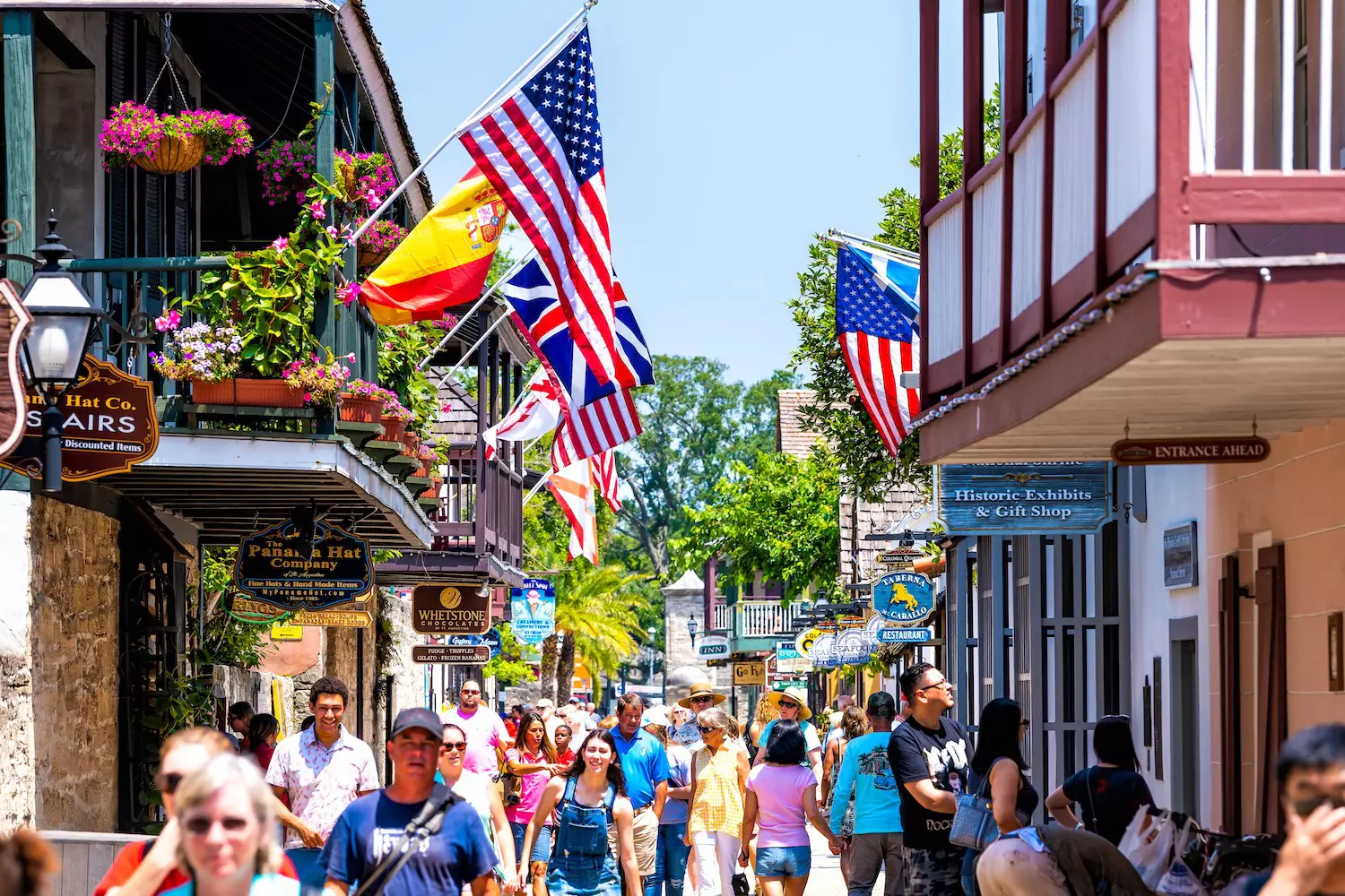 People shopping on St George St by stores, shops and restaurants American and international flags, St Augustine, Florida, USA