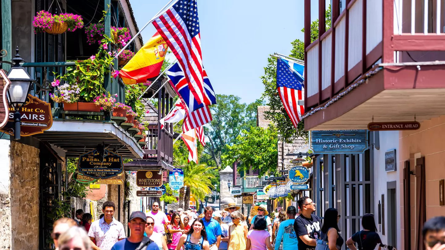 People shopping on St George St by stores, shops and restaurants American and international flags, St Augustine, Florida, USA