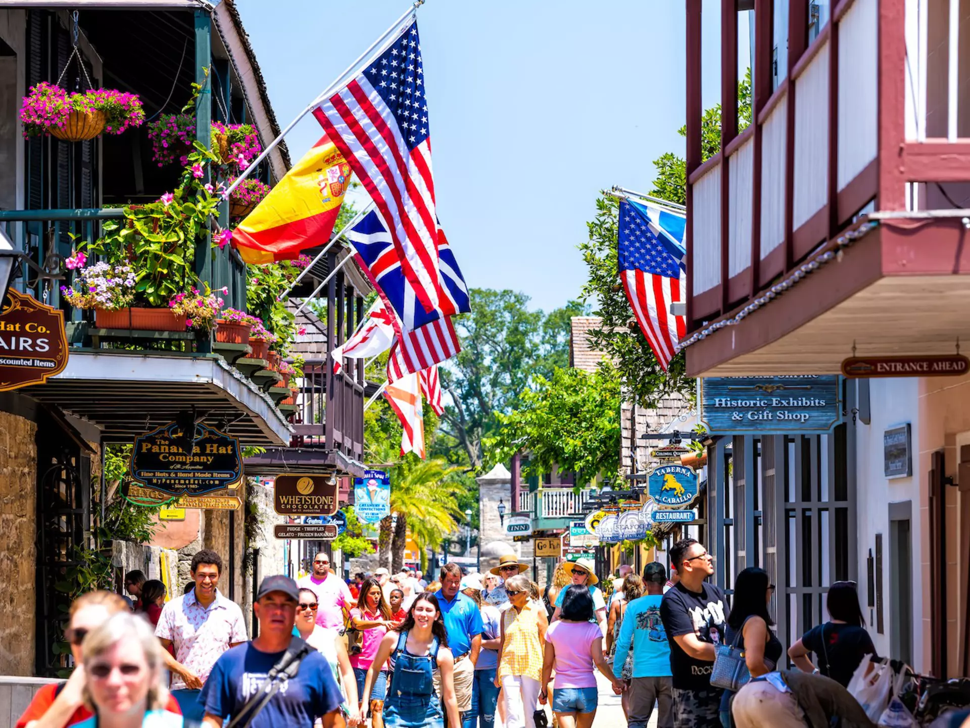 People shopping on St George St by stores, shops and restaurants American and international flags, St Augustine, Florida, USA