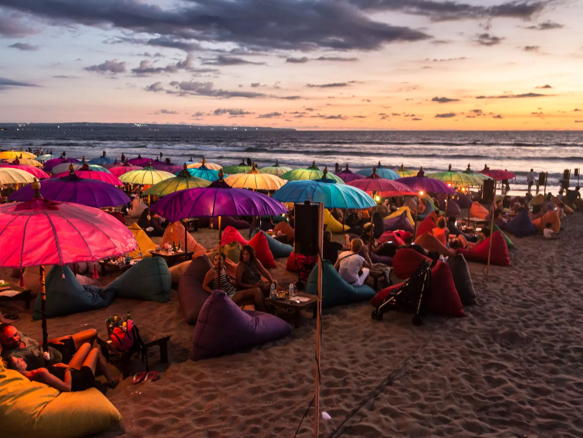 February 19, 2016: A crowd of people share food and drink under colourful umbrellas during sunset on Kuta beach.
628994390
Life, Landscape - Scenery, Editorial, Crowded, Nightlife, Crowd, Tree, Water, Southeast Asia, Lifestyles, Travel Destinations, Horizontal, Sky, Drink, Night, Dusk, Light - Natural Phenomenon, Photography, People, Building Exterior, Food, Asia, Tourist, Restaurant, Beach, Outdoors, Sea, Asian and Indian Ethnicities, Kuta, Parasol, Bar - Drink Establishment, Walking, Nature, Tourist Resort, Indonesia, Seminyak, Beer Bottle, Sofa, Majestic, Famous Place, Sand, East Asian Ethnicity, Tourism, Bali, Young Adult, Landscape, Mass - Unit of Measurement, Fun, Party - Social Event, Travel, Beach Party, Sunset, East Asian Culture, Arts Culture and Entertainment, Backpacker