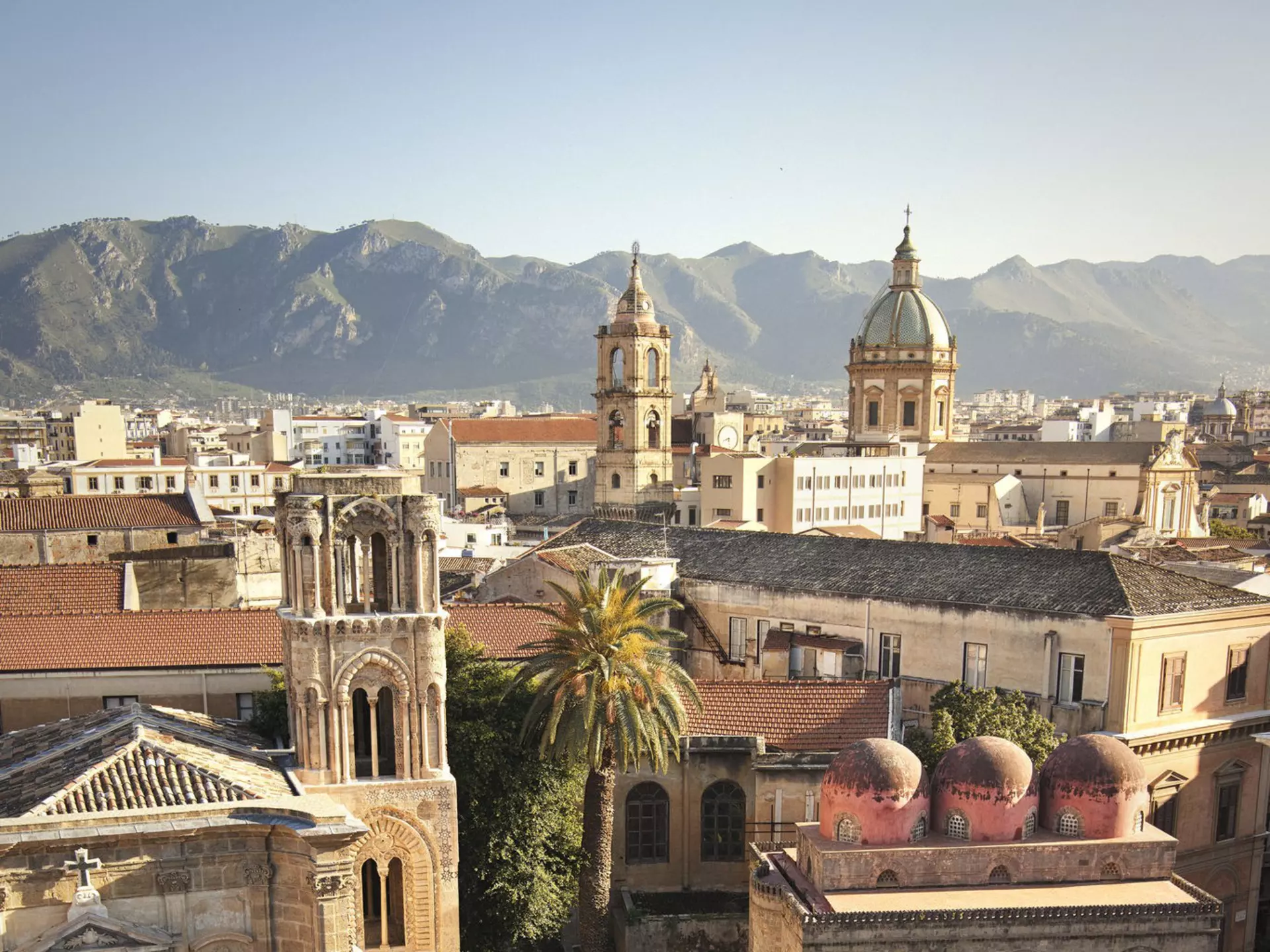 A city square in Palermo, Sicily, lined with churches. Hilltops are in the distance beyond the city