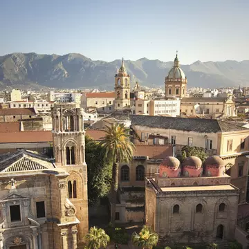 A city square in Palermo, Sicily, lined with churches. Hilltops are in the distance beyond the city