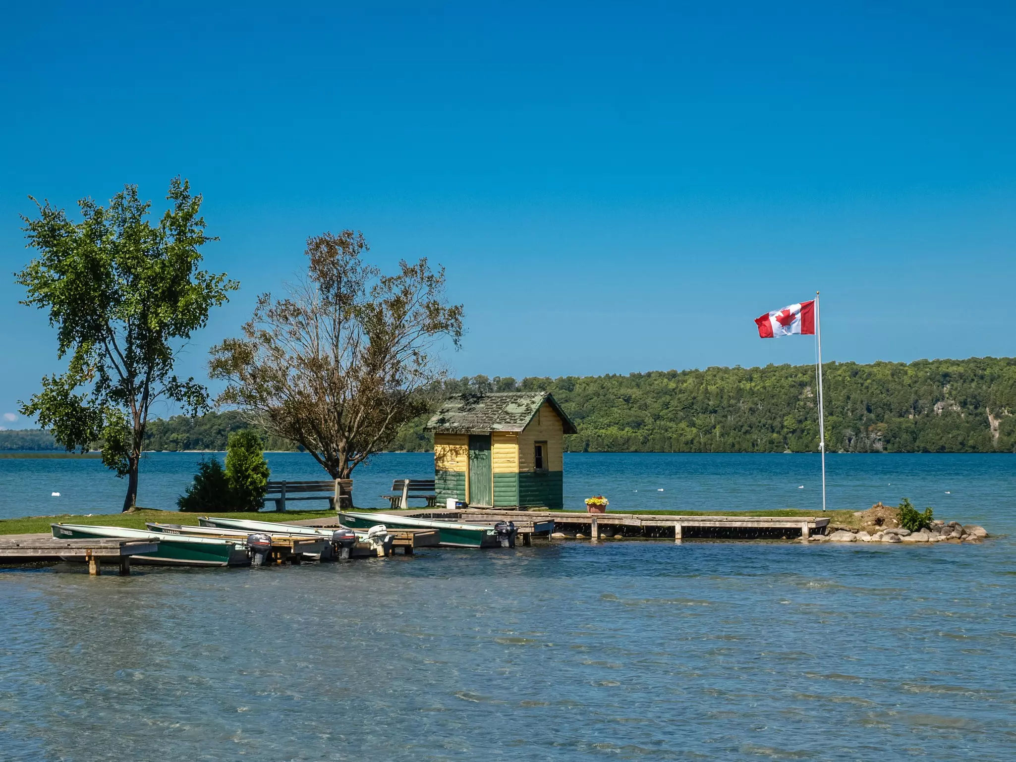 A flag flies on a small spit of land on an island in a lake.