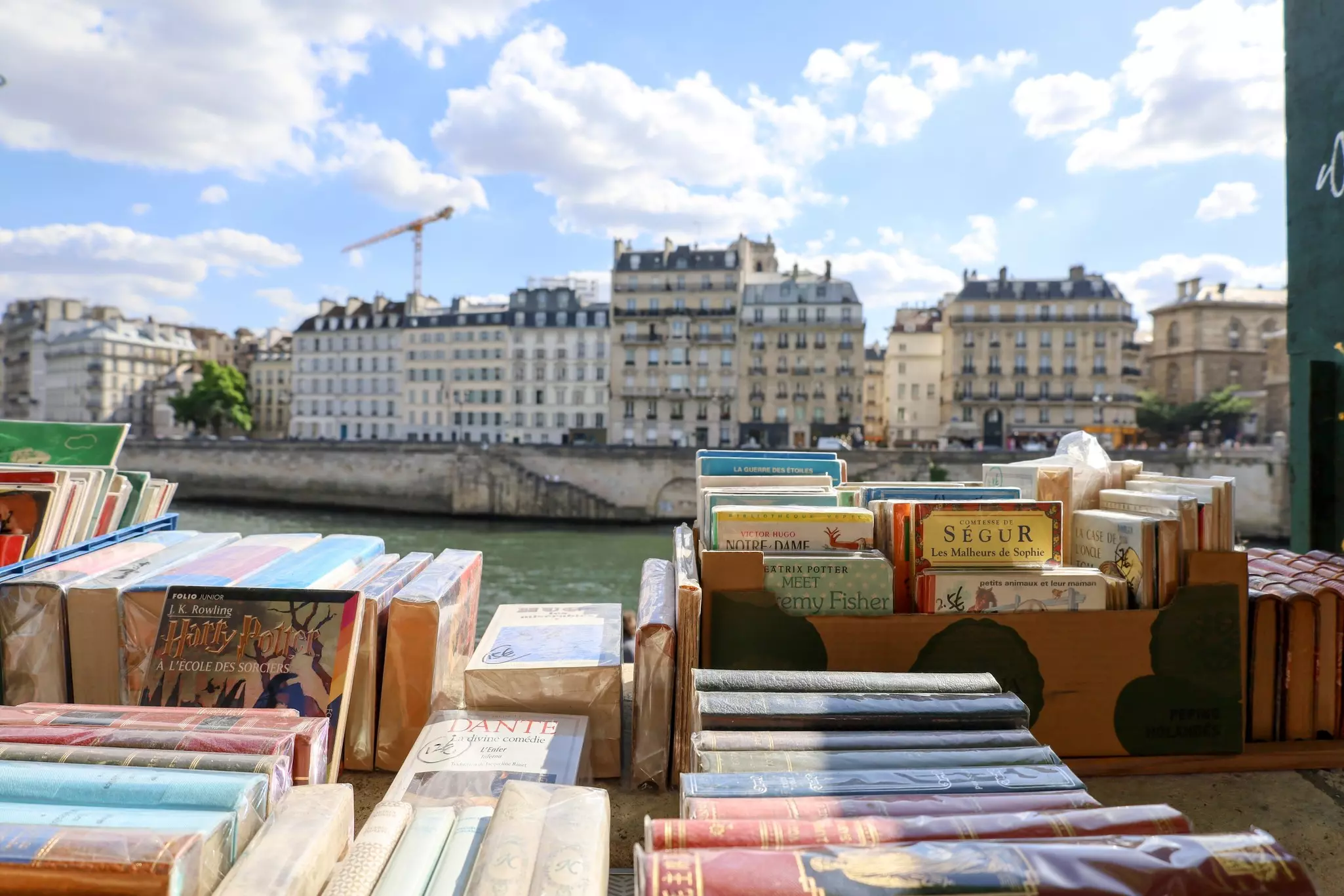 Books stacked for display at a stall by a river.