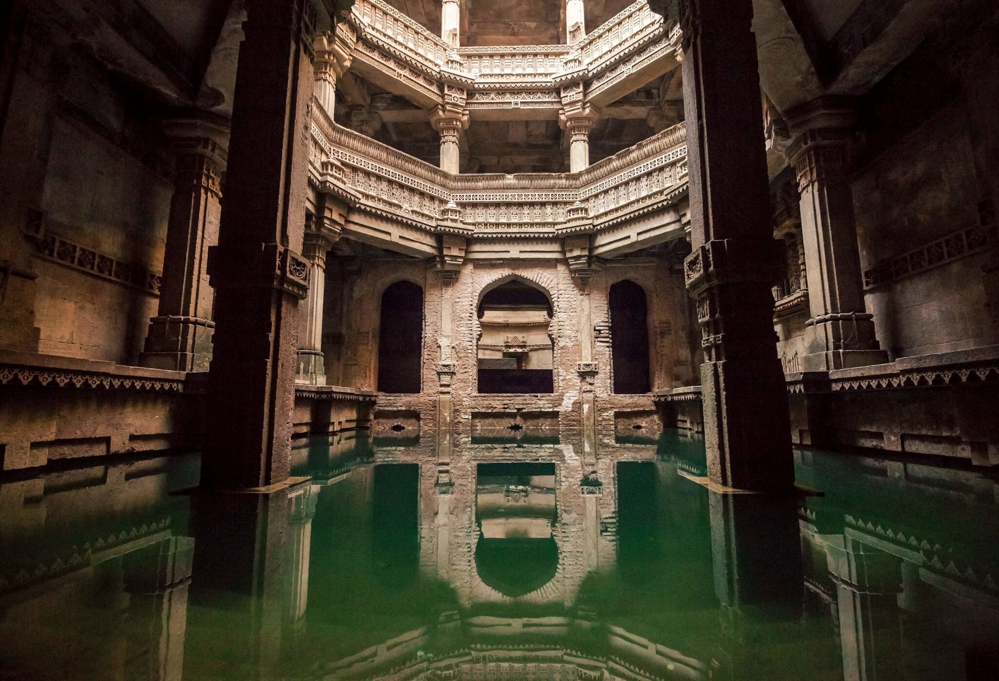 A large space with ornate pillars forming a canopy over a well filled with water