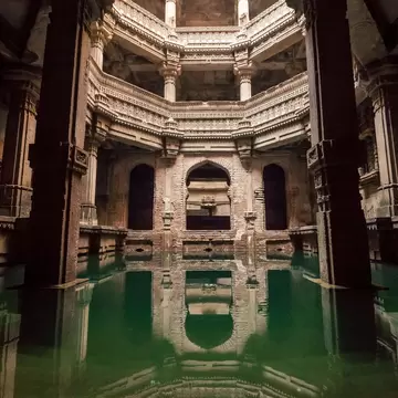 A large space with ornate pillars forming a canopy over a well filled with water