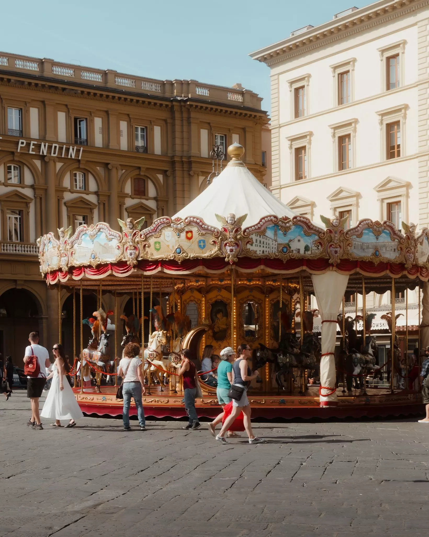 People walk around an old Tuscan carousel in Florence.