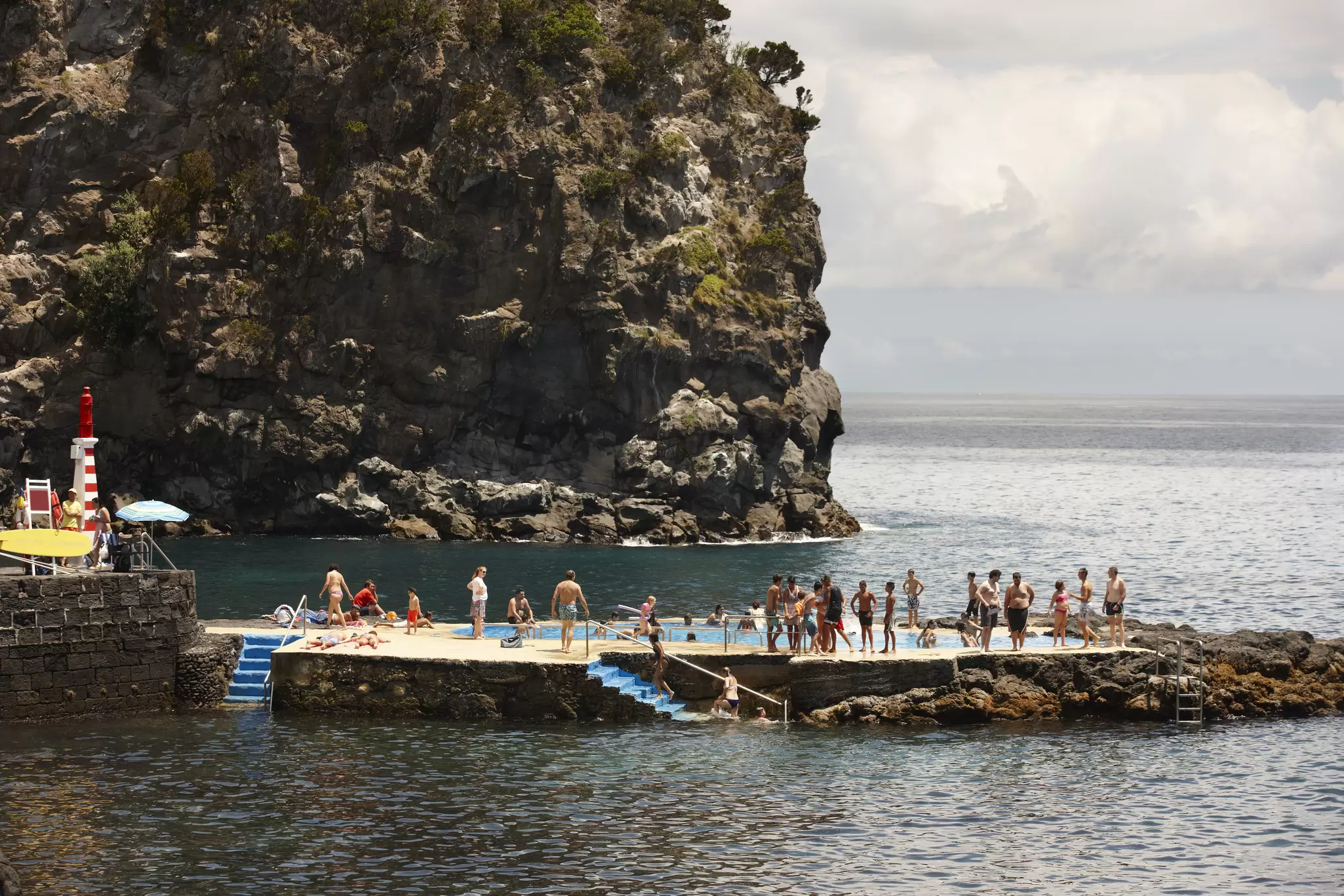 People queue up to jump in a rock pool in the Atlantic Ocean
