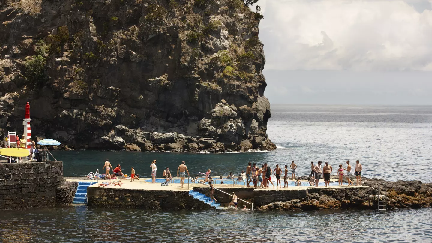 People queue up to jump in a rock pool in the Atlantic Ocean