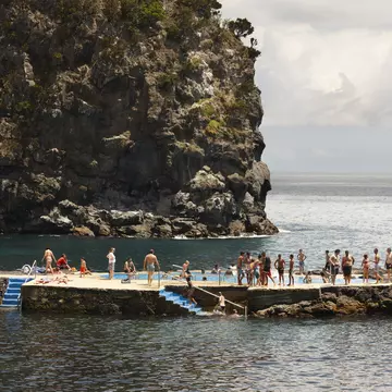 People queue up to jump in a rock pool in the Atlantic Ocean