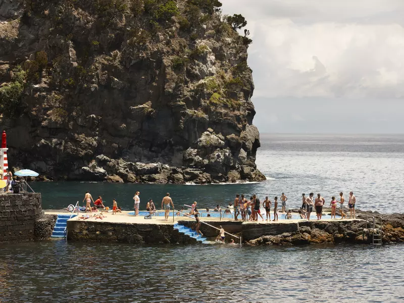 People queue up to jump in a rock pool in the Atlantic Ocean