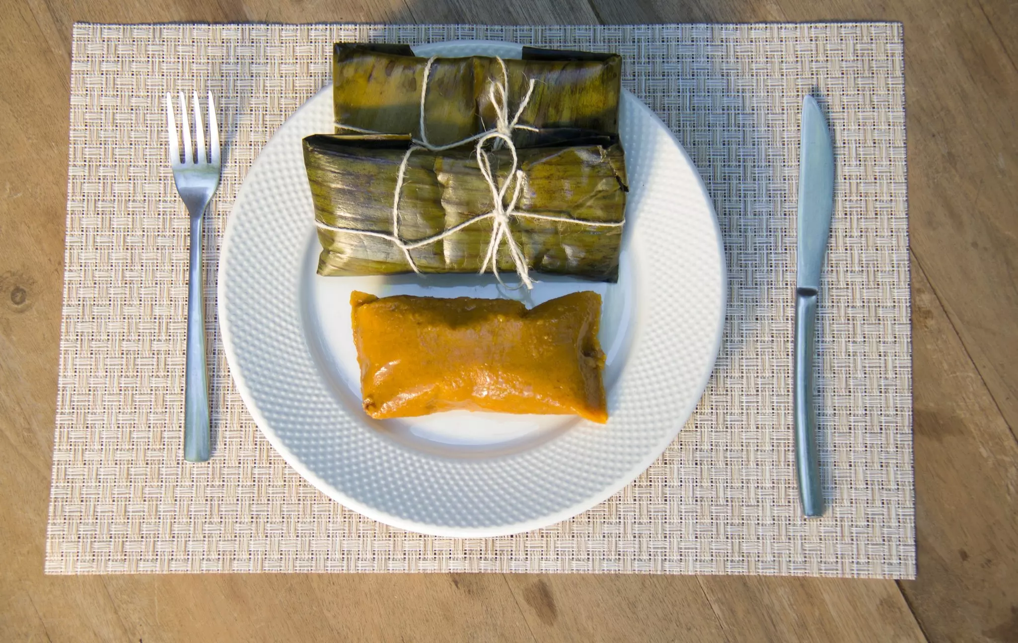 A plate of Dominican pasteles en hoja – plantain dough filled with meat wrapped in plantain leaves.