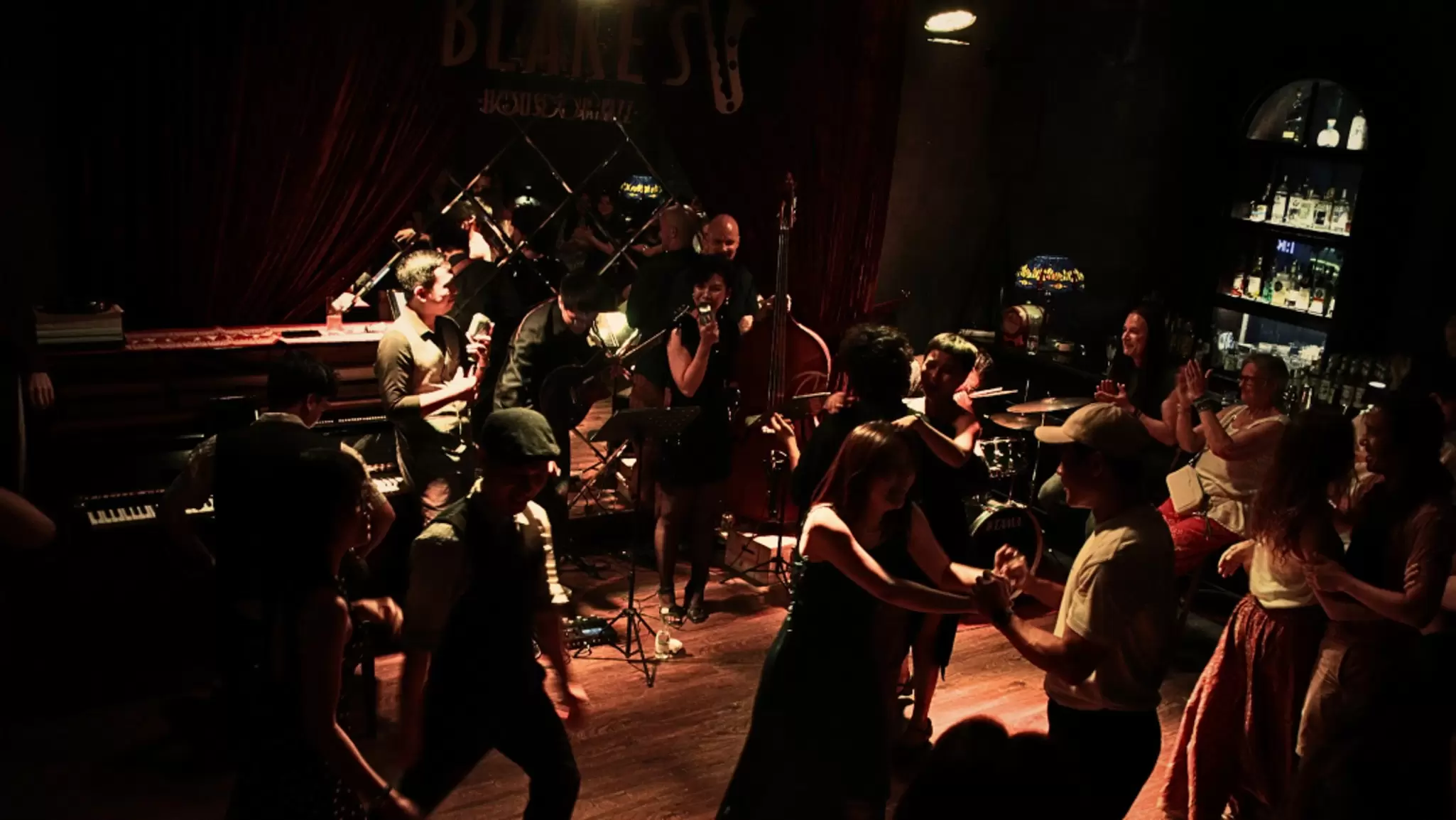 People dance in front of a jazz band in a dark club in Hanoi, Vietnam. 