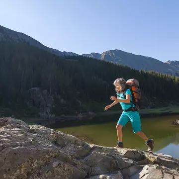 A woman hiking on a boulder near a lake