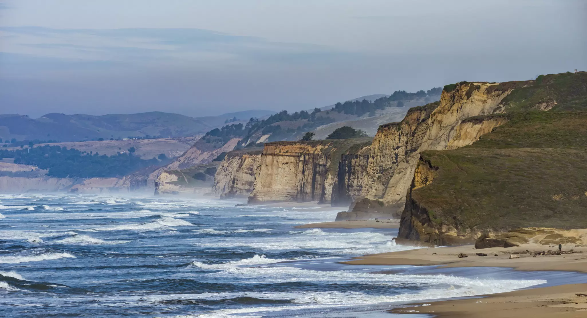 Waves crash at cliffs.