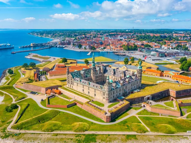 Panorama of a castle with a sea and city in the distance on a sunny day.