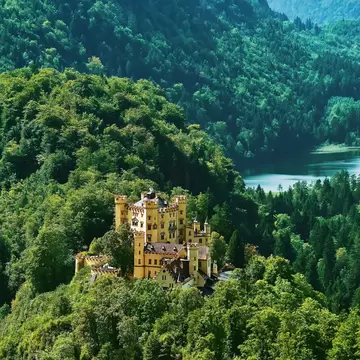 Exterior of Hohenschwangau Castle (Schloss Hohenschwangau or Upper Swan County Palace) set among mountainous forests.