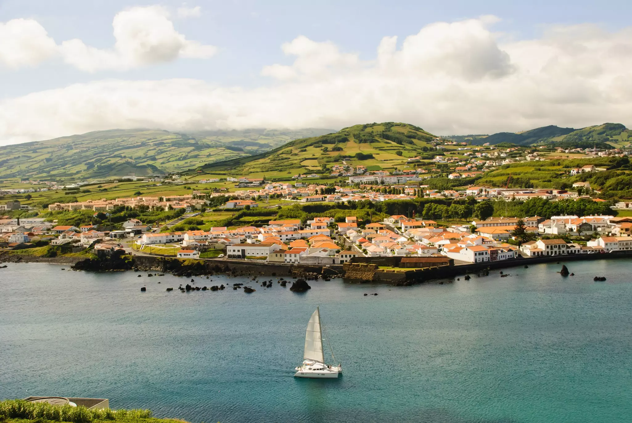 View to Horta with bay, Faial island, Azores, with a catamaran in the water in the foreground