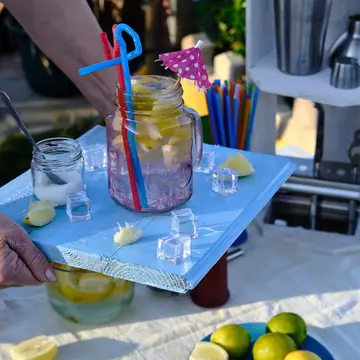 Waitress brings a cocktail on her blue wooden tray