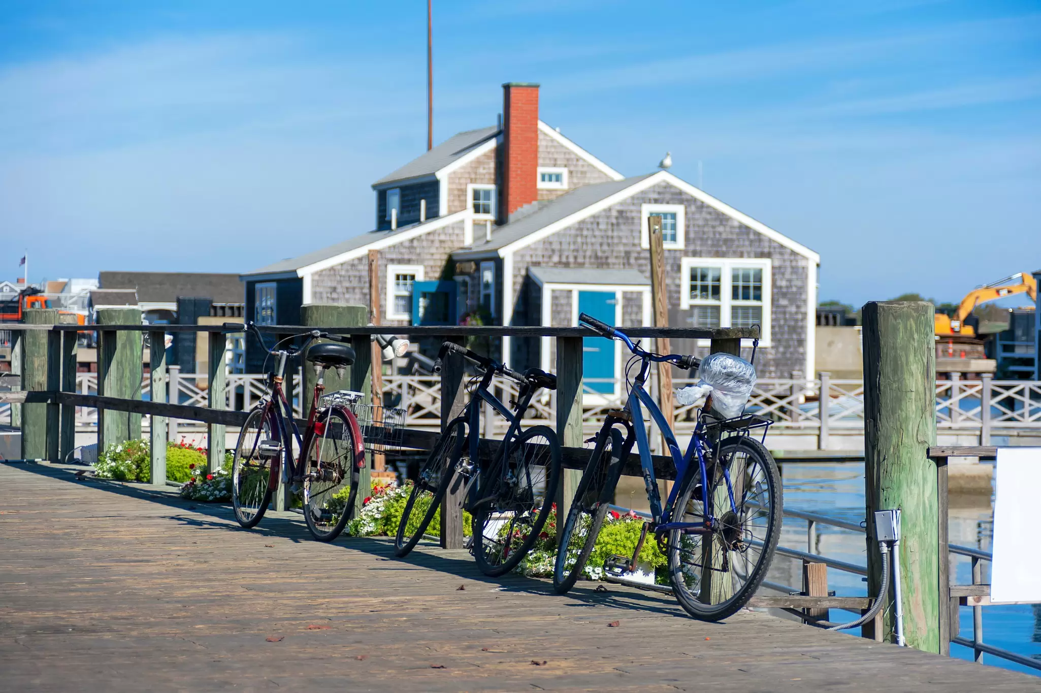 Tourist Bikes in Nantucket Harbour in the sunny morning with wooden buildings behind