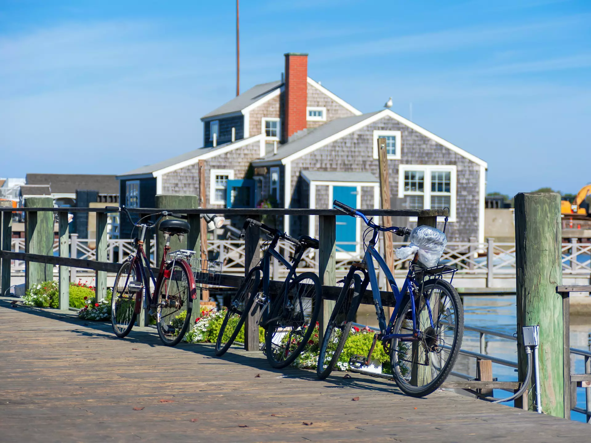 Tourist Bikes in Nantucket Harbour in the sunny morning with wooden buildings behind