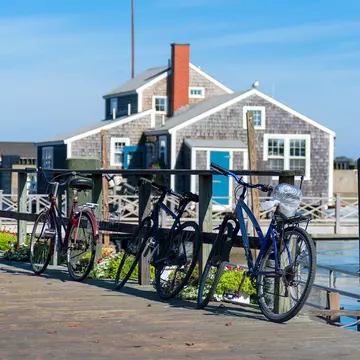 Tourist Bikes in Nantucket Harbour in the sunny morning with wooden buildings behind
