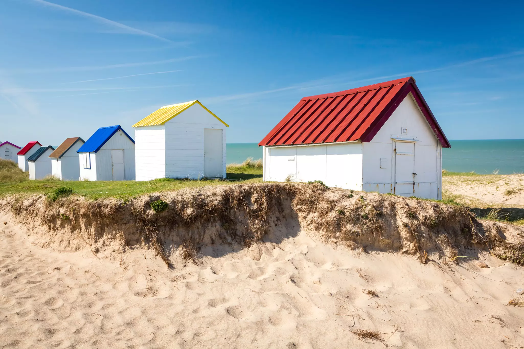 Colorful wooden beach cabins in the dunes, Gouville-sur-Mer, Normandy.