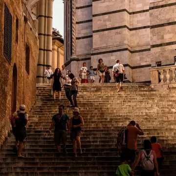 Crowds of tourists walking up steep steps on a sunny day.