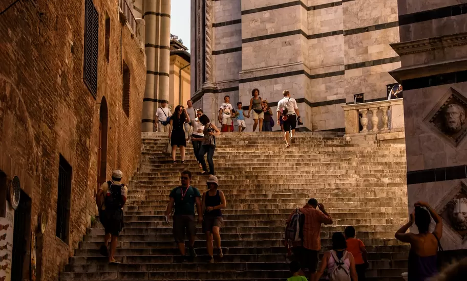 Crowds of tourists walking up steep steps on a sunny day.