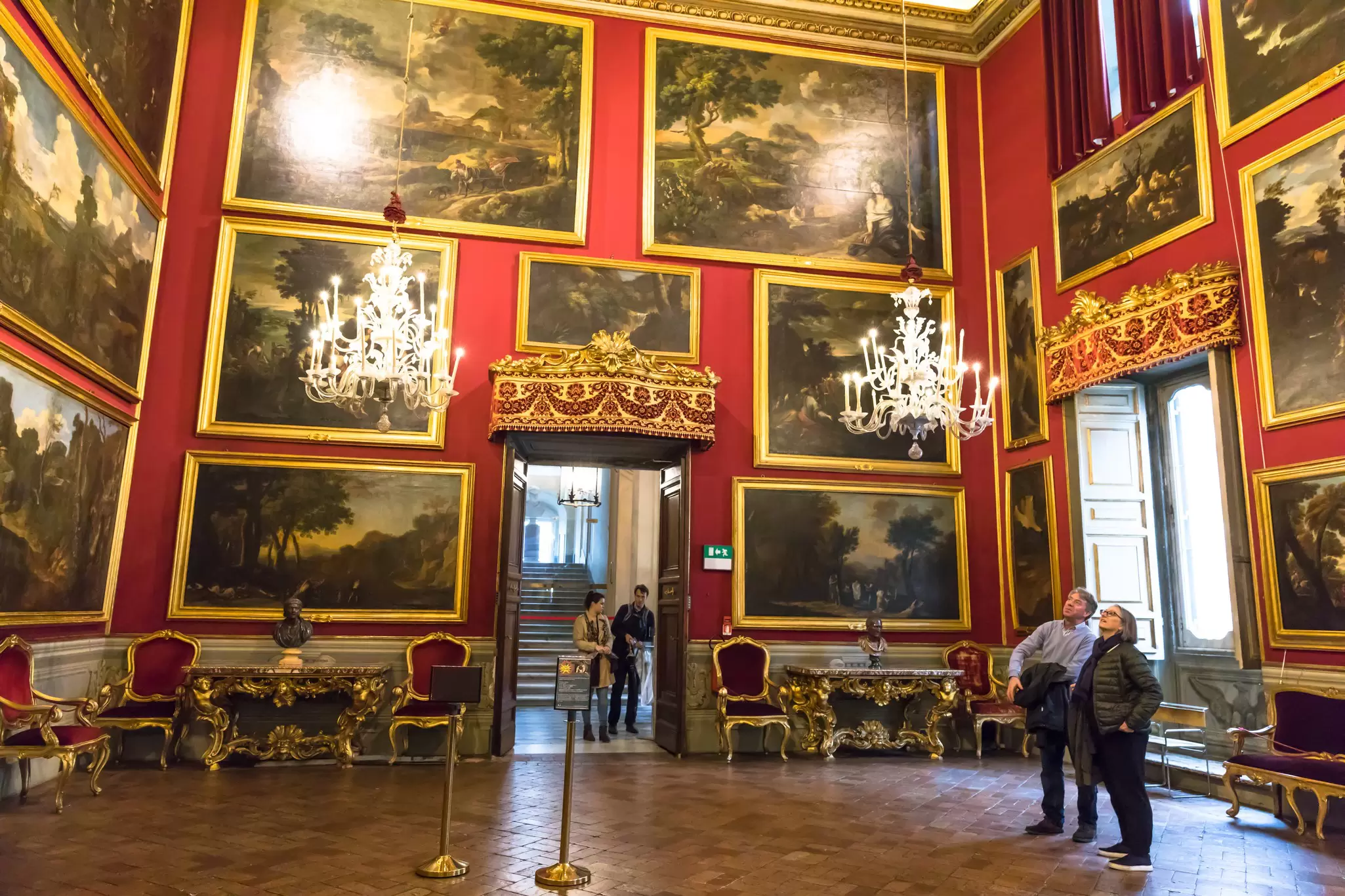 Visitors looking at paintings in the Salone del Poussin in the Galleria Doria Pamphilj in Rome, Italy.