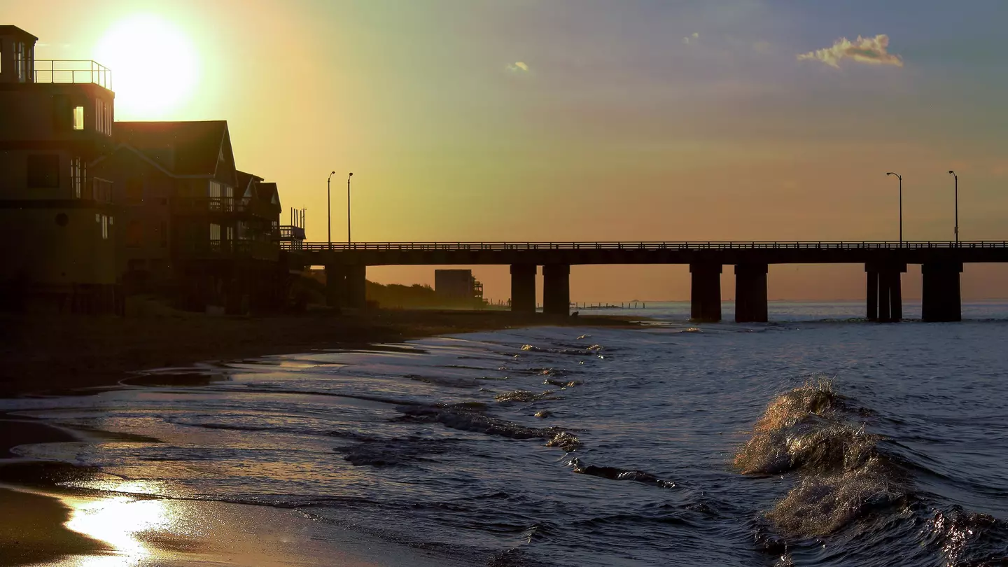 A beach scene with a bridge in the background