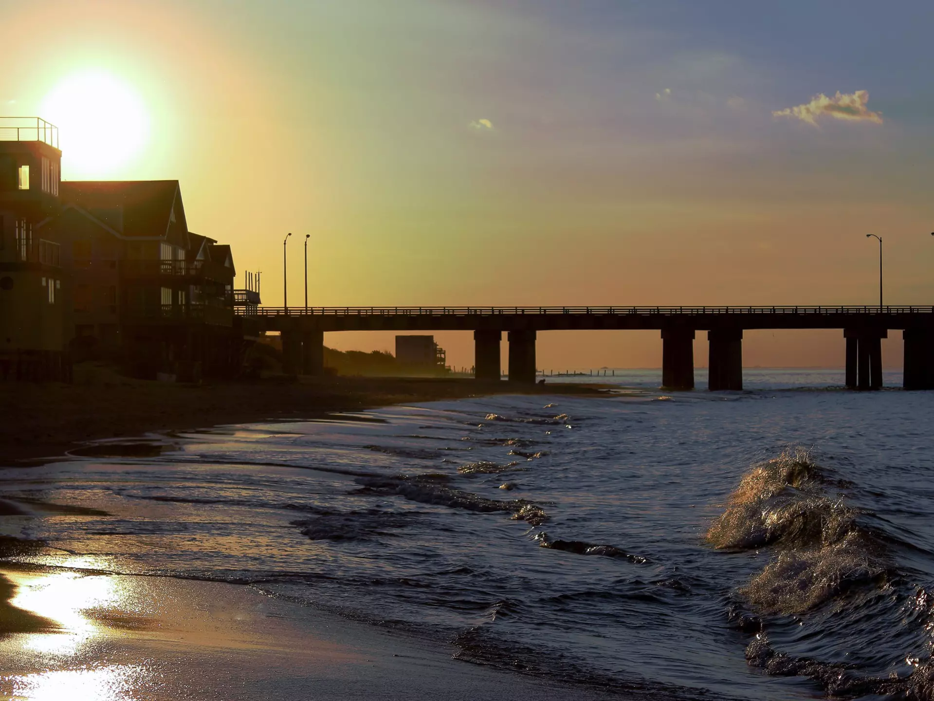 A beach scene with a bridge in the background